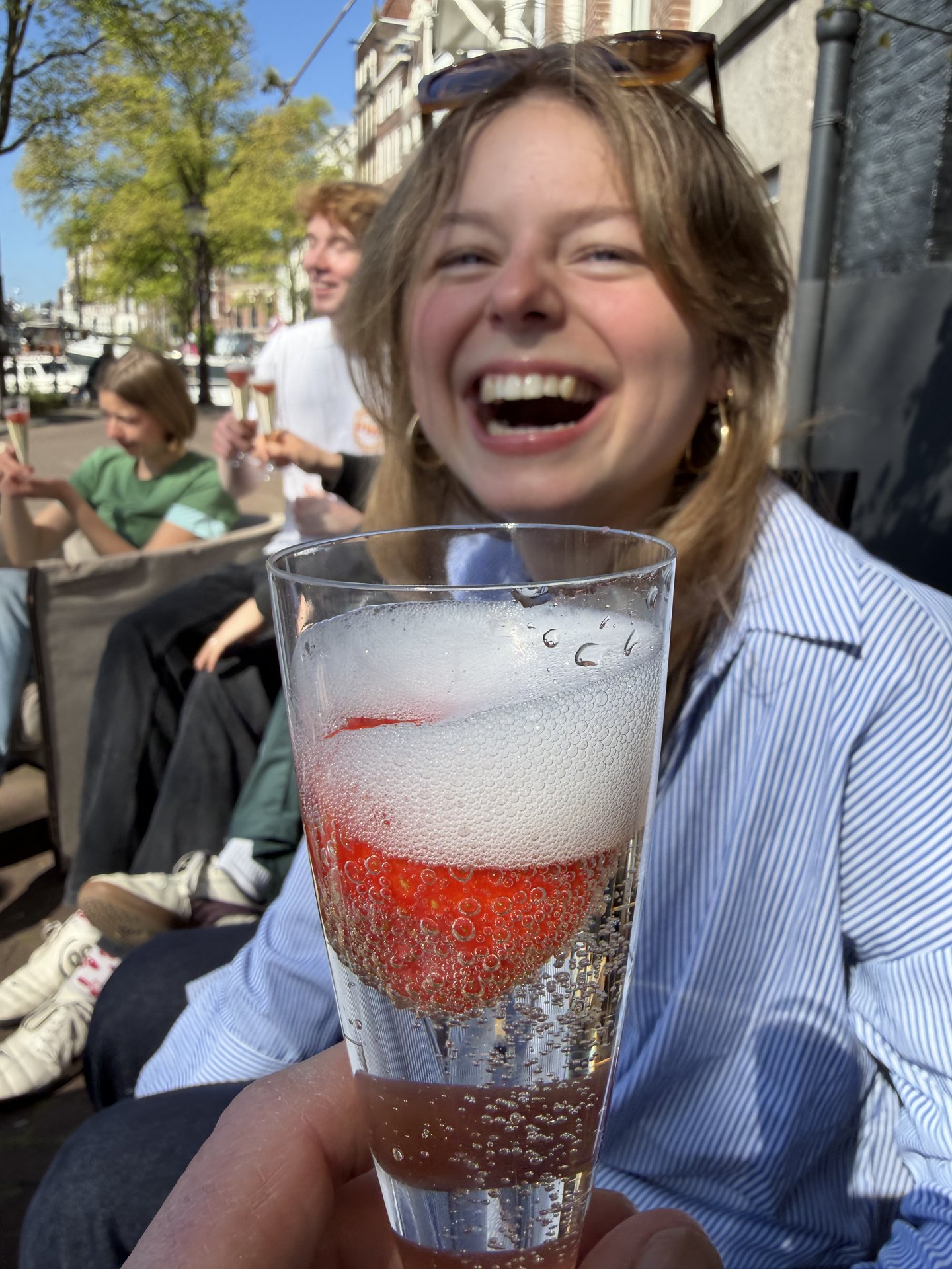 This vibrant photo captures a group of friends enjoying drinks on an outdoor terrace at Staalkade, Centrum, Amsterdam